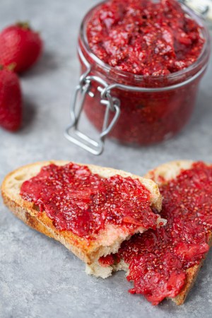 strawberry chia jam in a jar next to two slices of toast