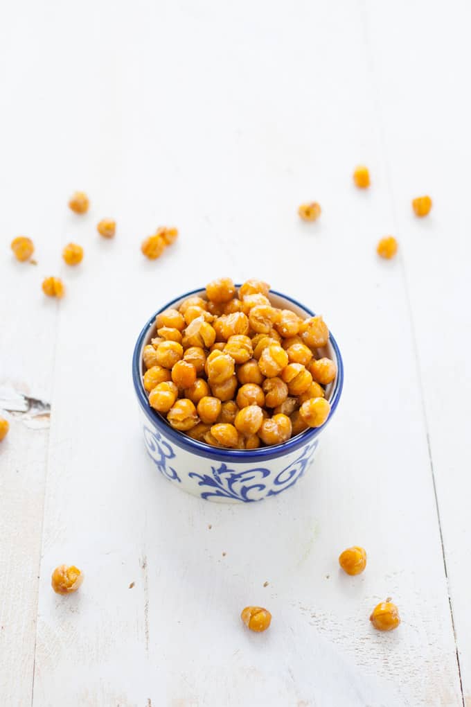 Small blue and white bowl filled with golden crispy chickpeas on a white background