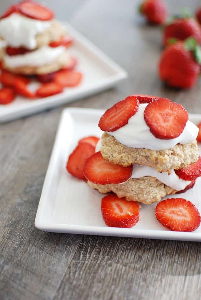 two plates of individual strawberry shortcakes with extra fresh strawberries