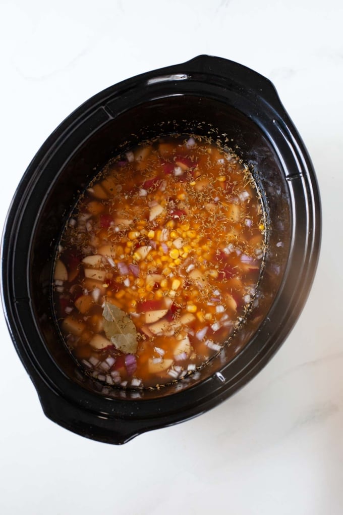 potato corn chowder ingredients and vegetable broth in slow cooker