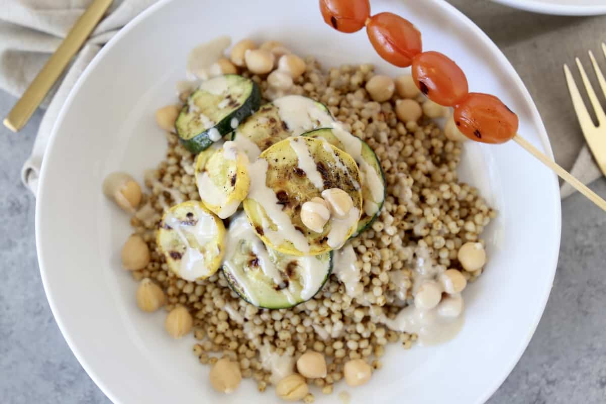 veggies, chickpeas, and tahini sauce served on a white plate