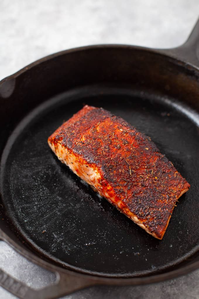 cooked blackened salmon filet in a black cast iron pan