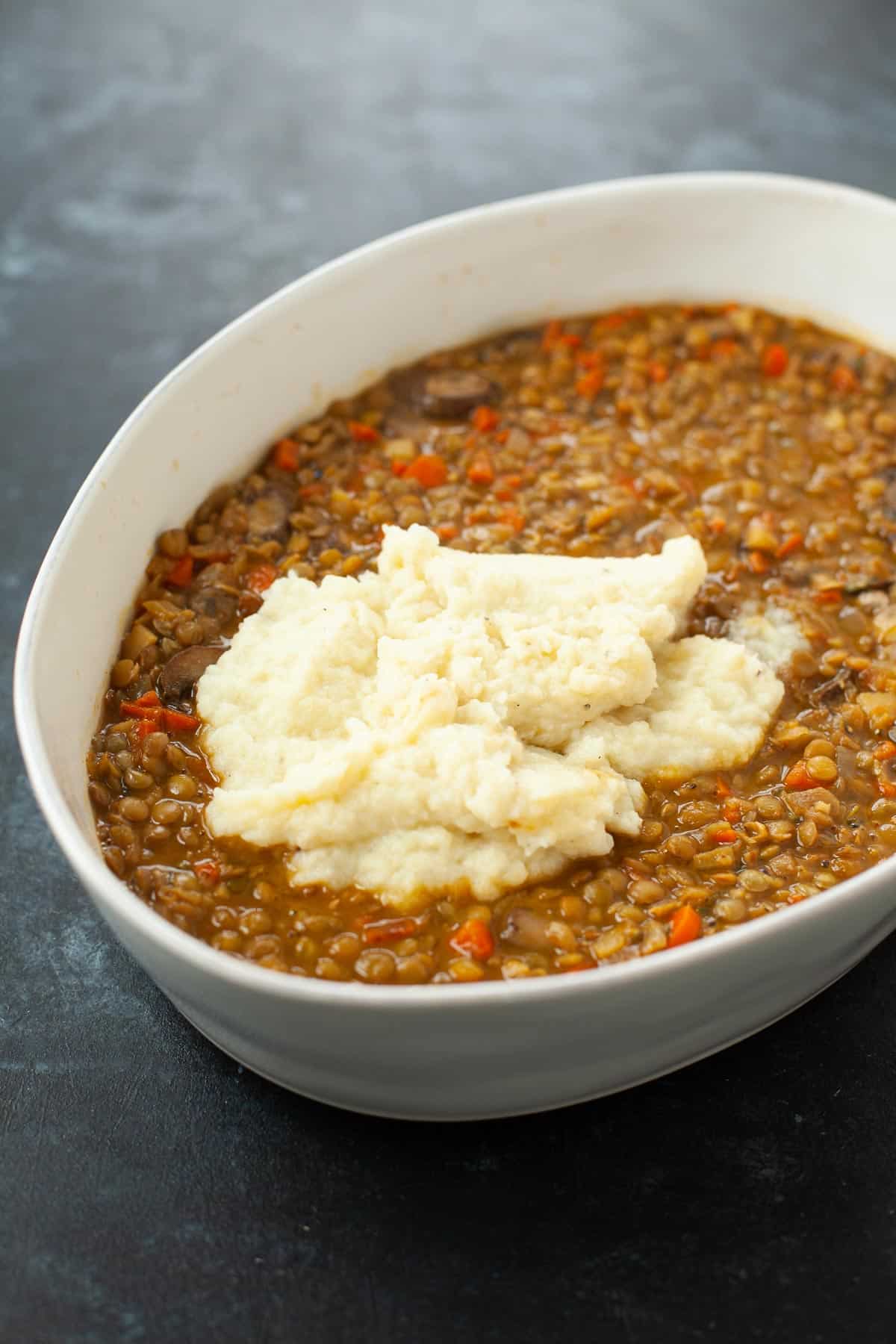 mashed potatoes scooped on top of ingredients for vegan shepherd's pie