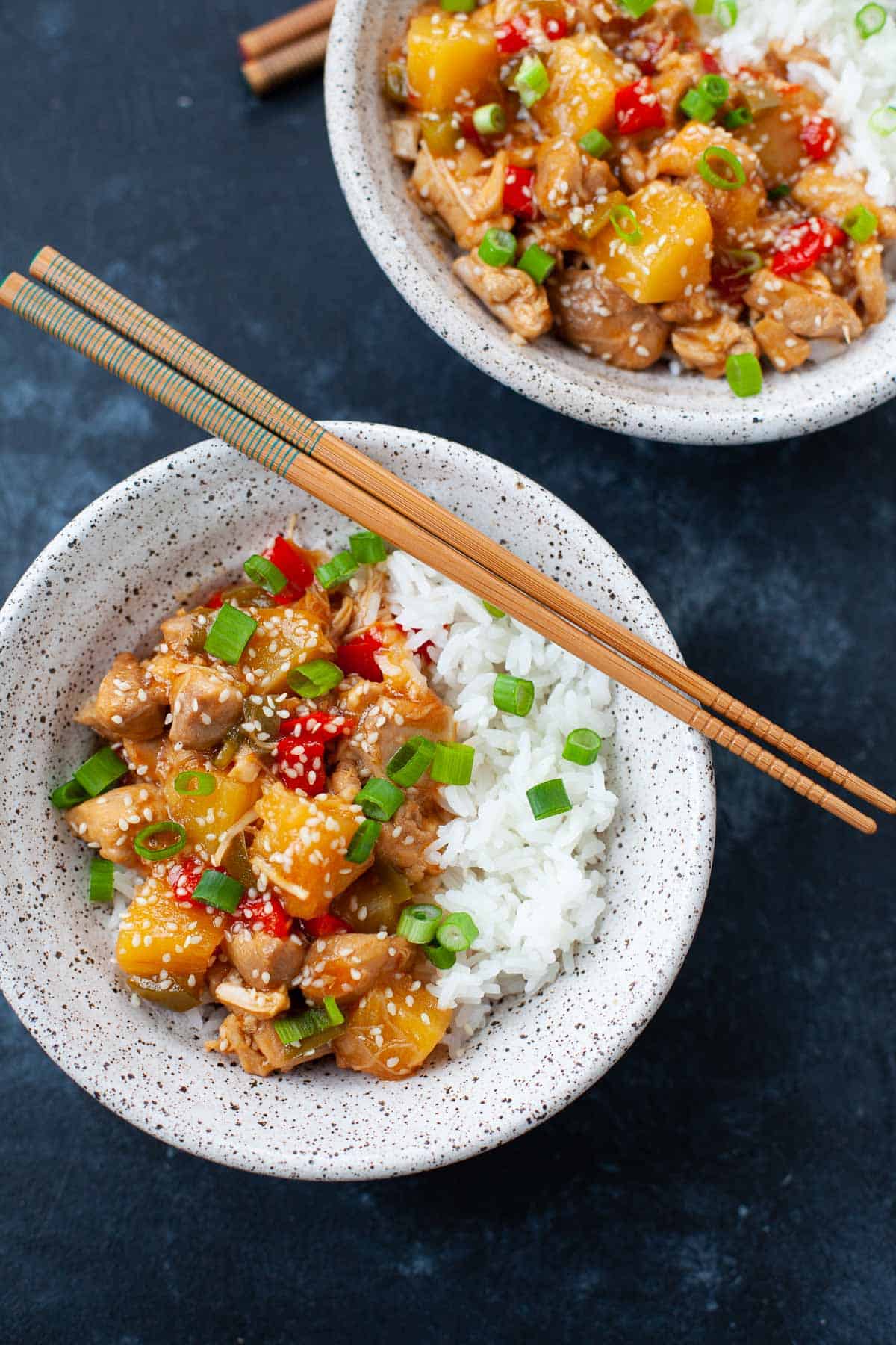 two bowls of sweet and sour chicken served with white rice