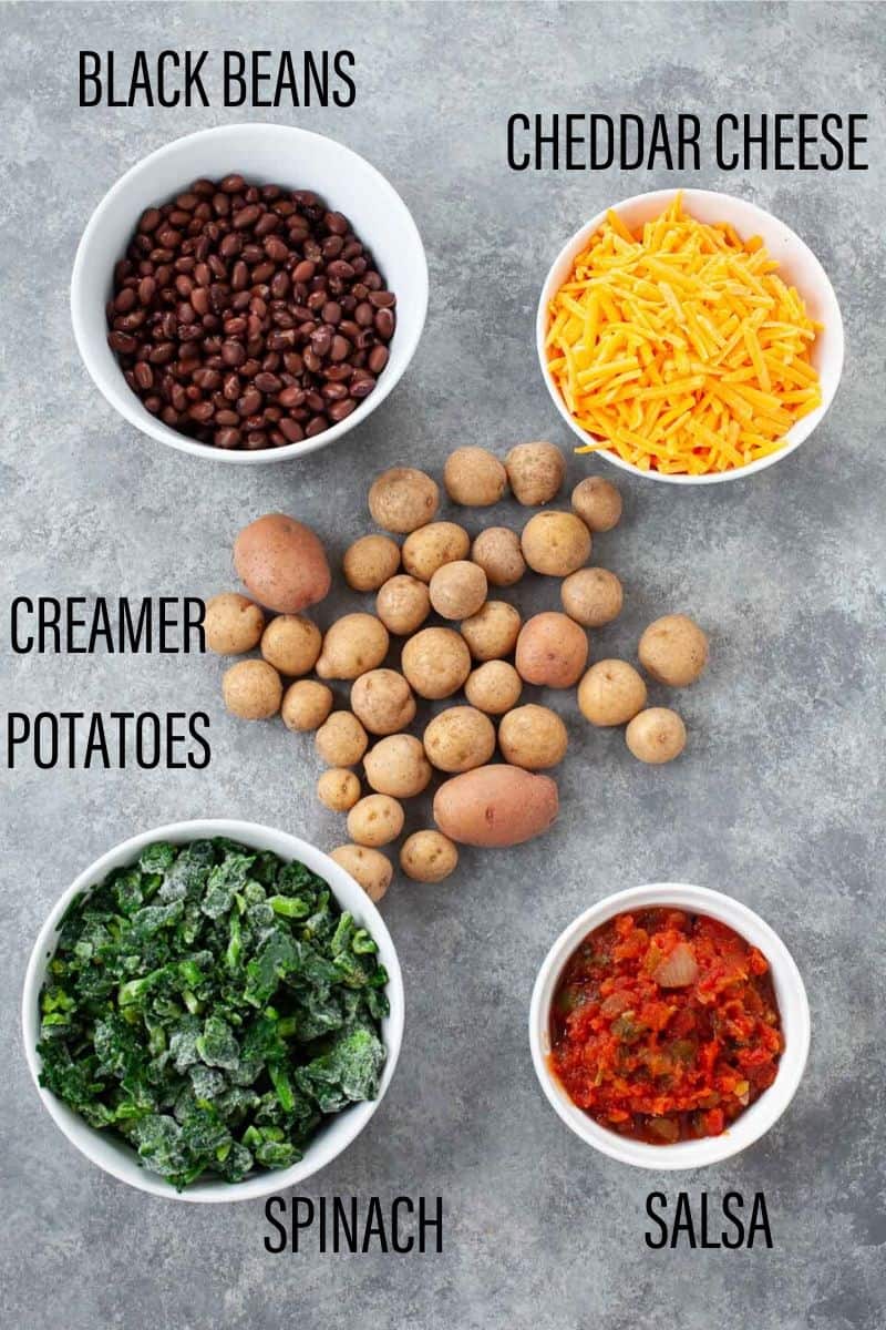 nacho ingredients black beans, cheddar cheese, spinach, salsa, creamer potatoes separated in white bowls