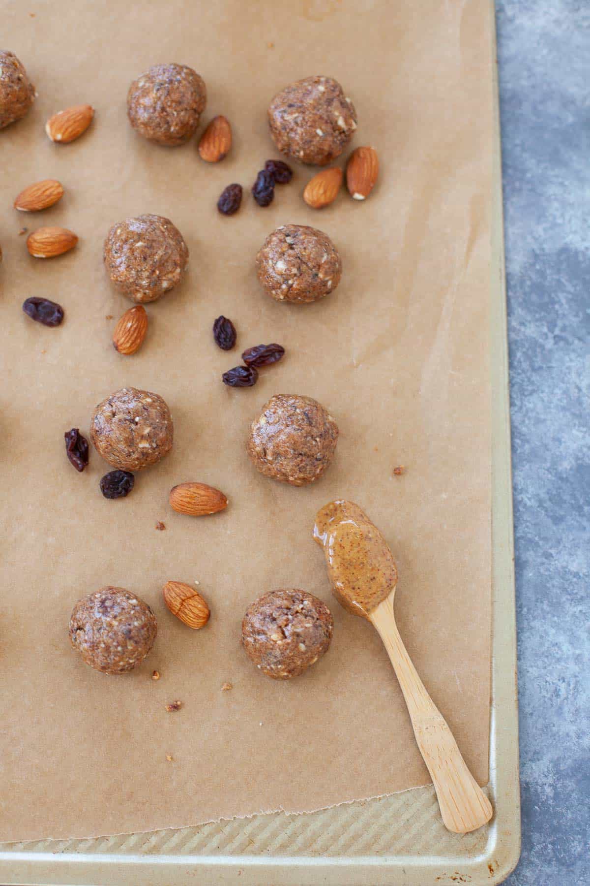 almond butter jelly balls with almonds and raisins on a baking sheet