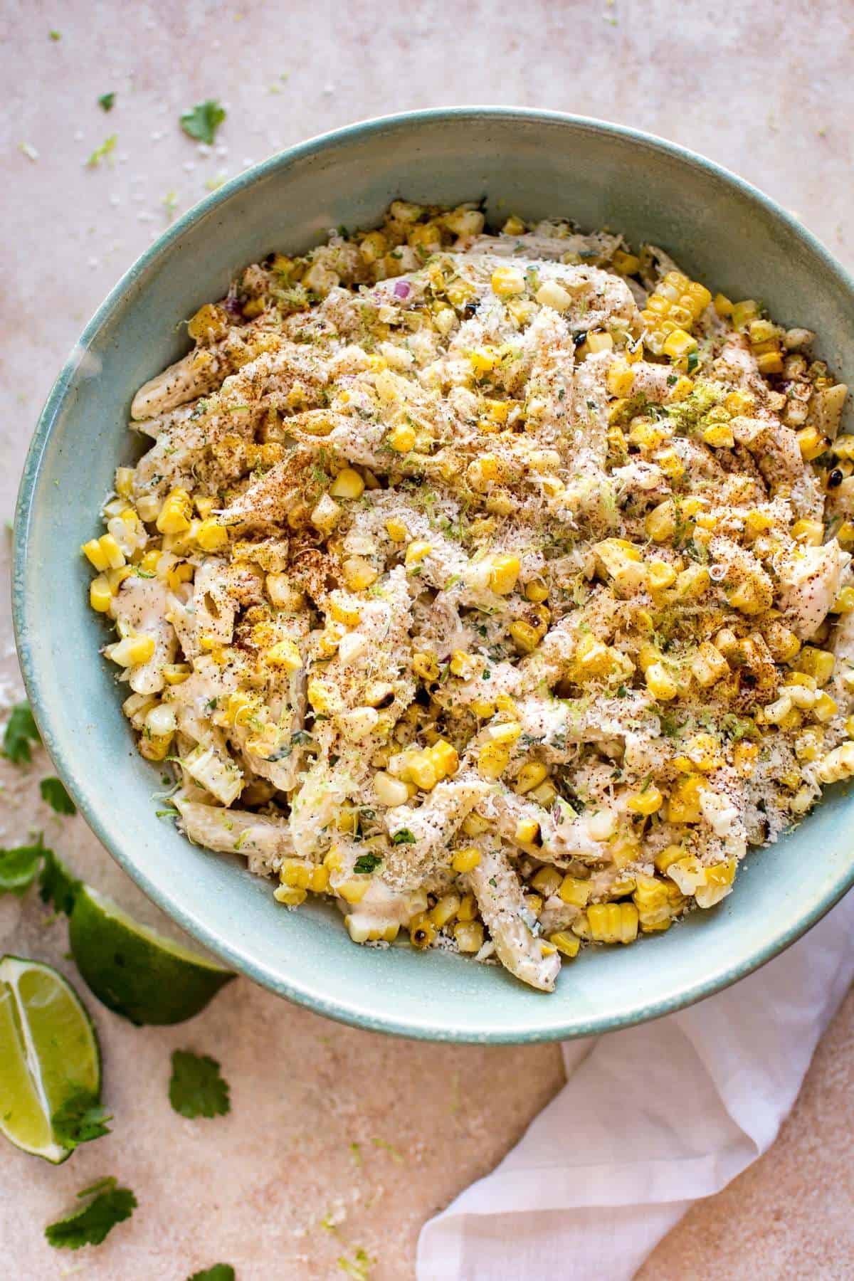 Mexican street corn pasta salad with shredded cheese and lime slices