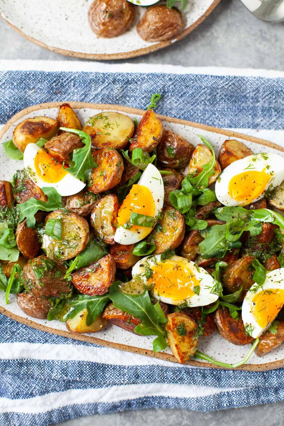 roasted potato salad with soft boiled eggs, arugula, and scallions