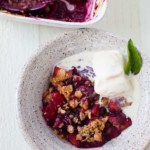 serving of Blueberry Peach Basil Crisp in a bowl with white baking dish next to it