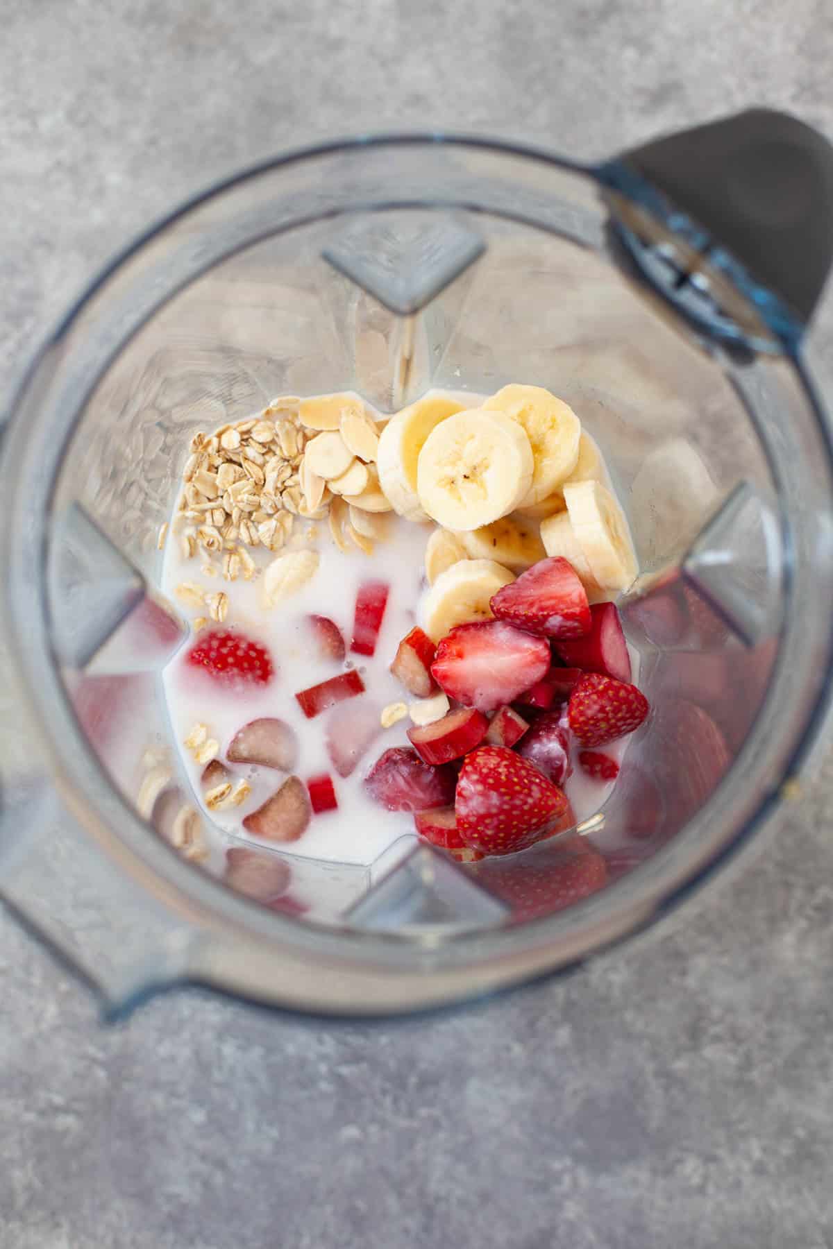 frozen strawberries, sliced banana, oats, and coconut milk placed inside of a blender