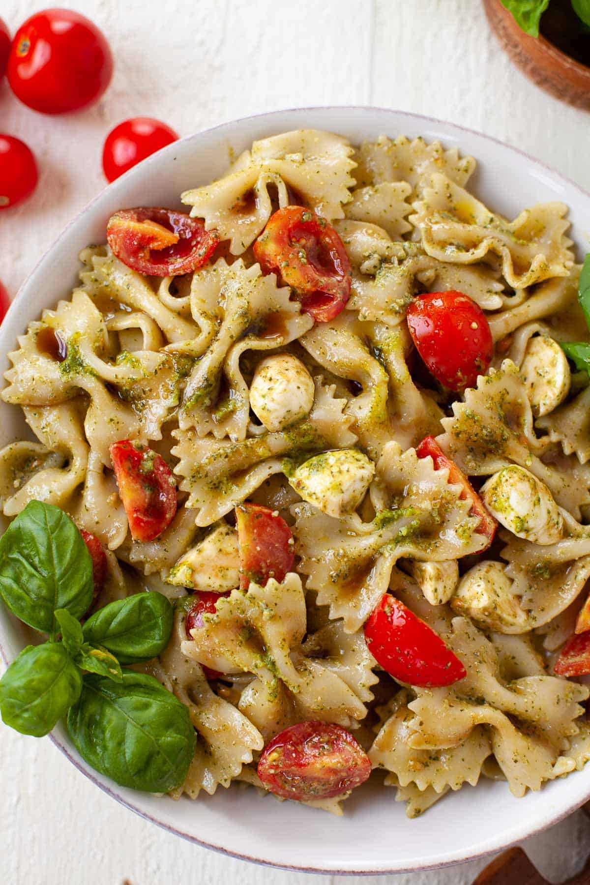 caprese pasta salad in a bowl with sliced tomatoes and fresh basil