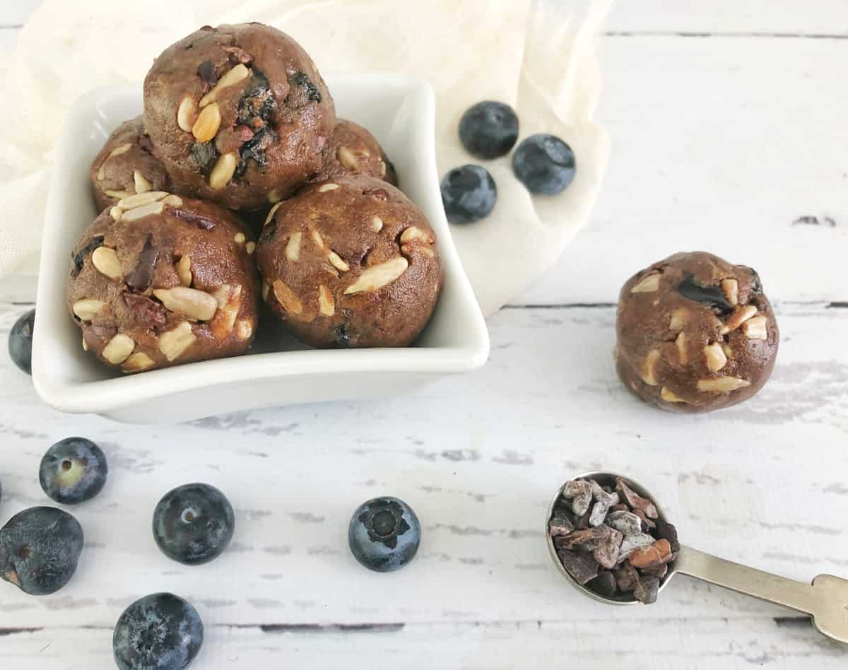 energy bites in bowl with cacao nibs and blueberries