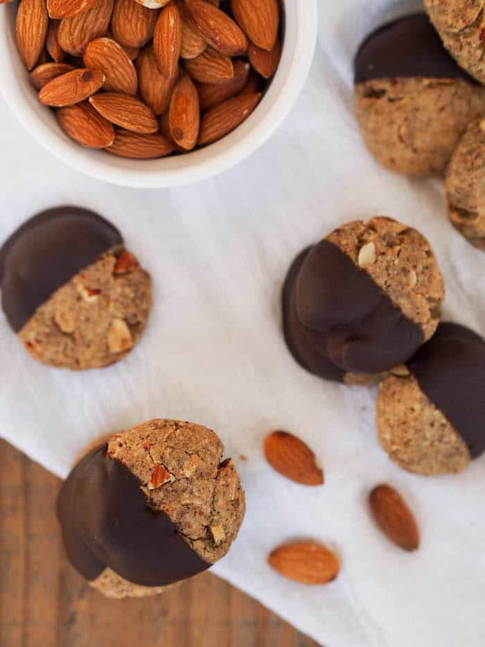 chai almond cookies dipped in dark chocolate with bowl of almonds
