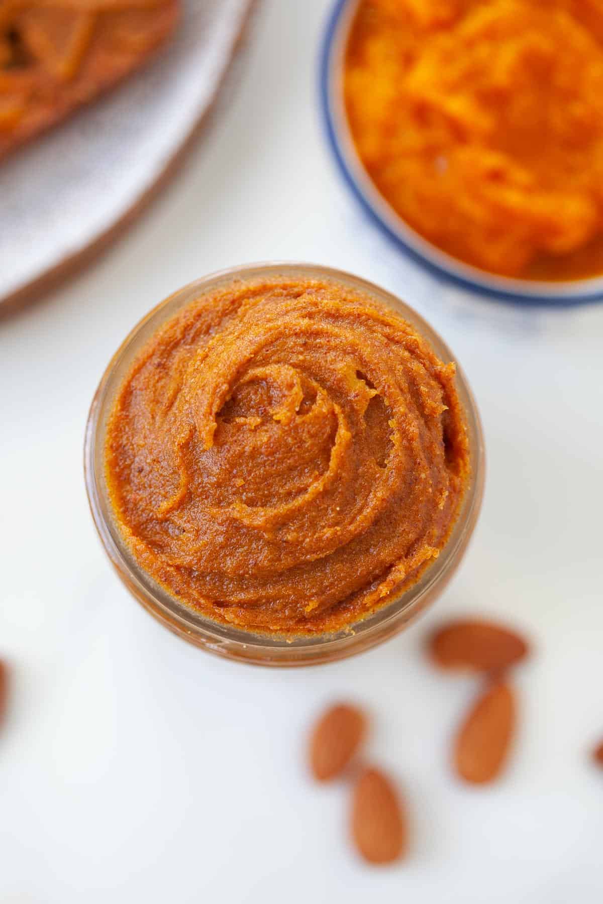 pumpkin almond butter in a mason jar with a bowl of pumpkin puree in background