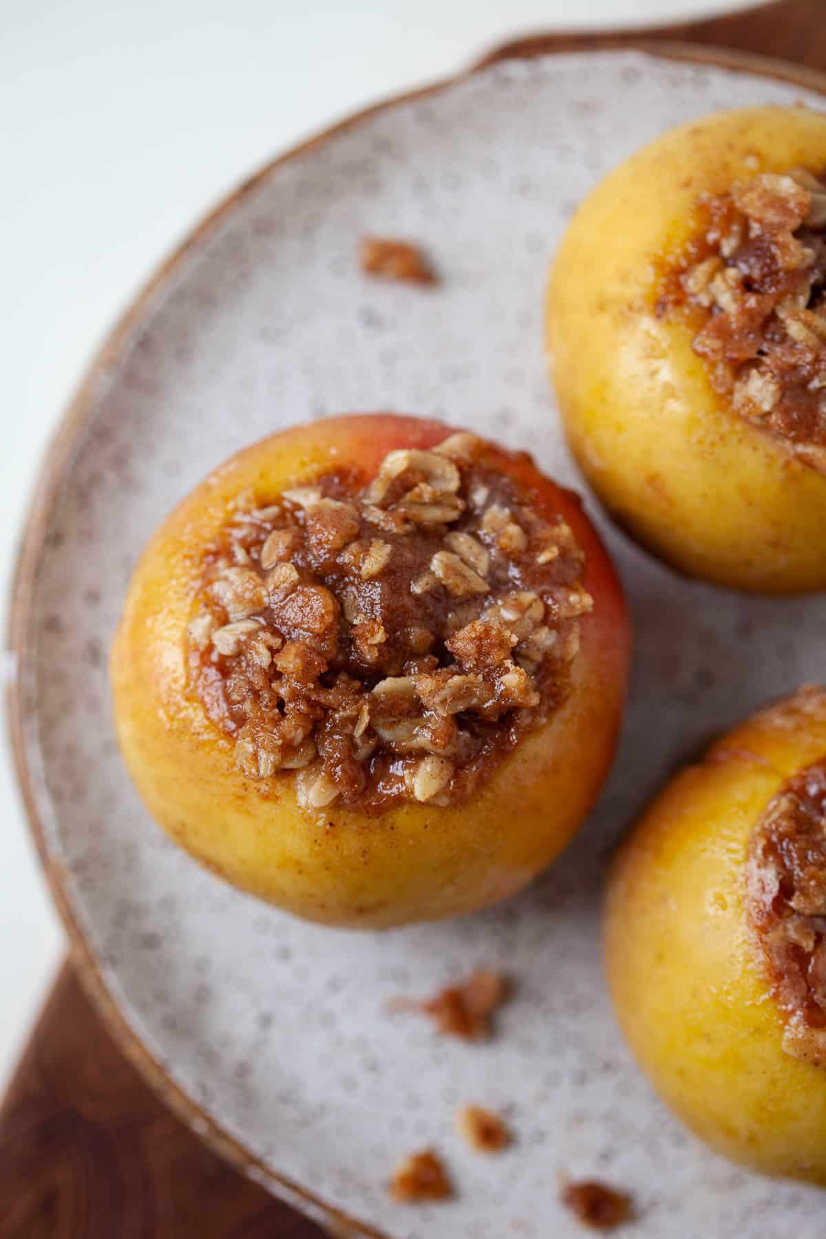 three baked apples with oat and cinnamon mixture in the center of the apples