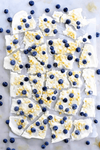 Blueberry Sweet Corn Frozen Greek Yogurt Bark broken up into pieces on a countertop with fresh blueberries