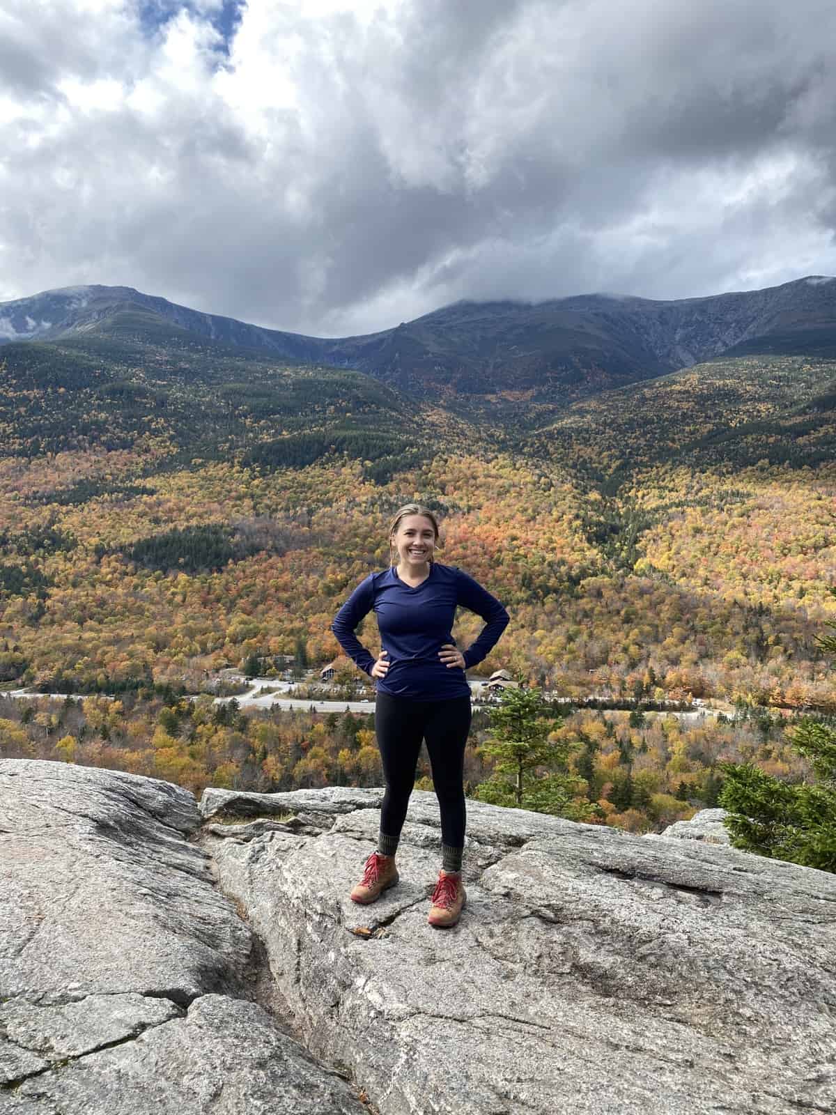 image of woman hiking in white mountains in new hampshire with fall foliage in background
