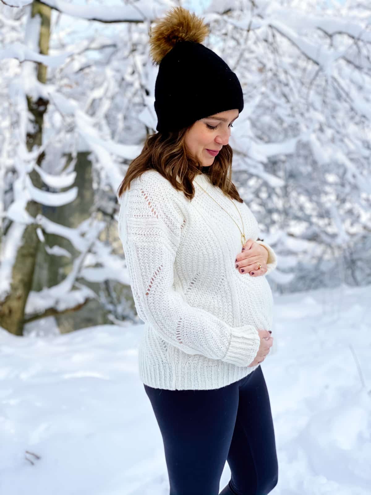 image of pregnant woman holding belly in the winter with snow in background