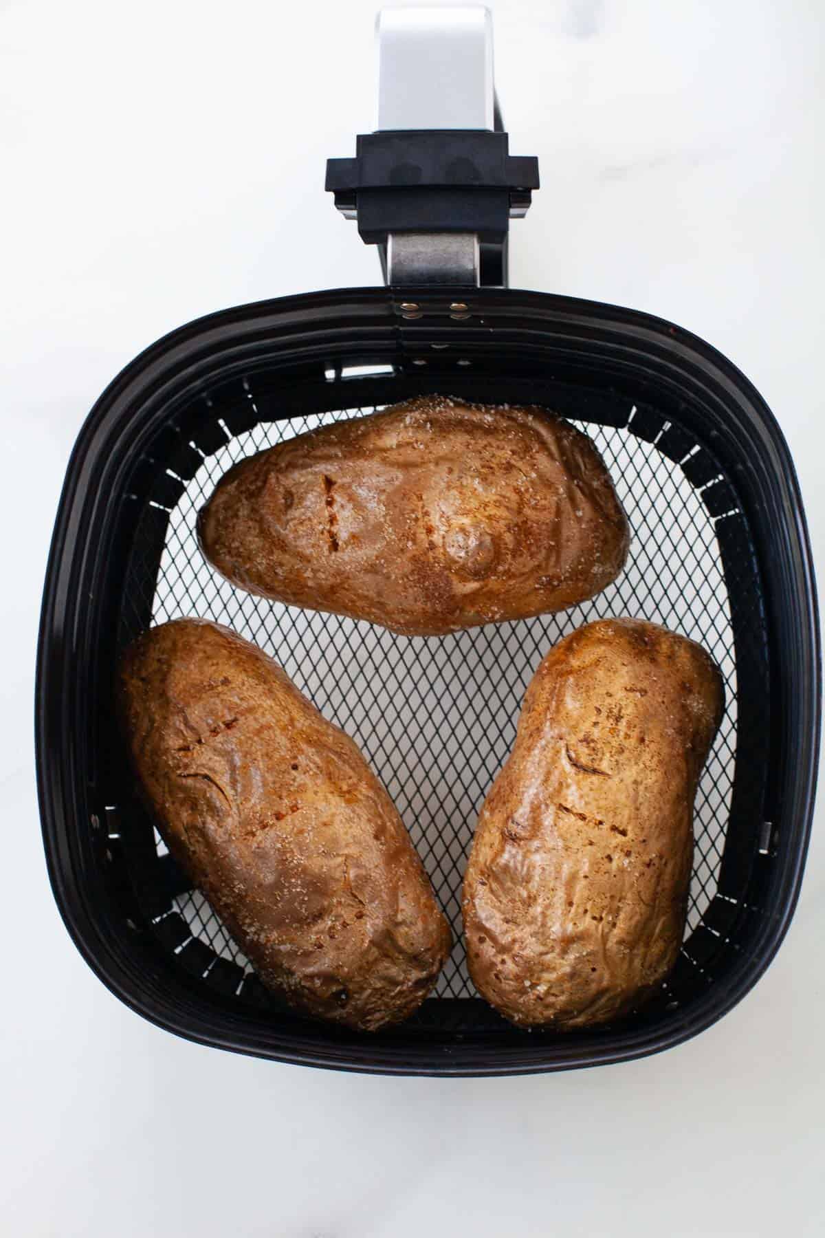 three potatoes placed inside of an air fryer