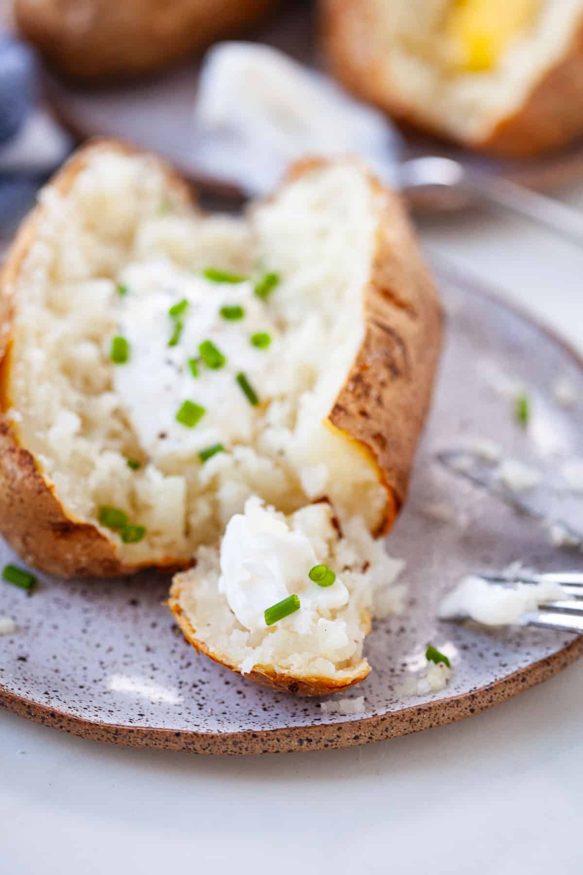 baked potato that's sliced in half with sour cream and sliced scallions on top