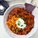 vegetarian chili with beans, quinoa, lentils, cocoa powder, tortilla chips, cheese, sour cream, and scallions