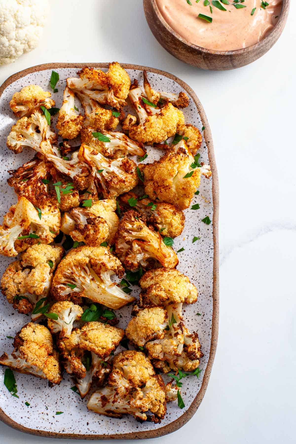 crispy crunchy golden brown air fryer cauliflower on large plate with dipping sauce