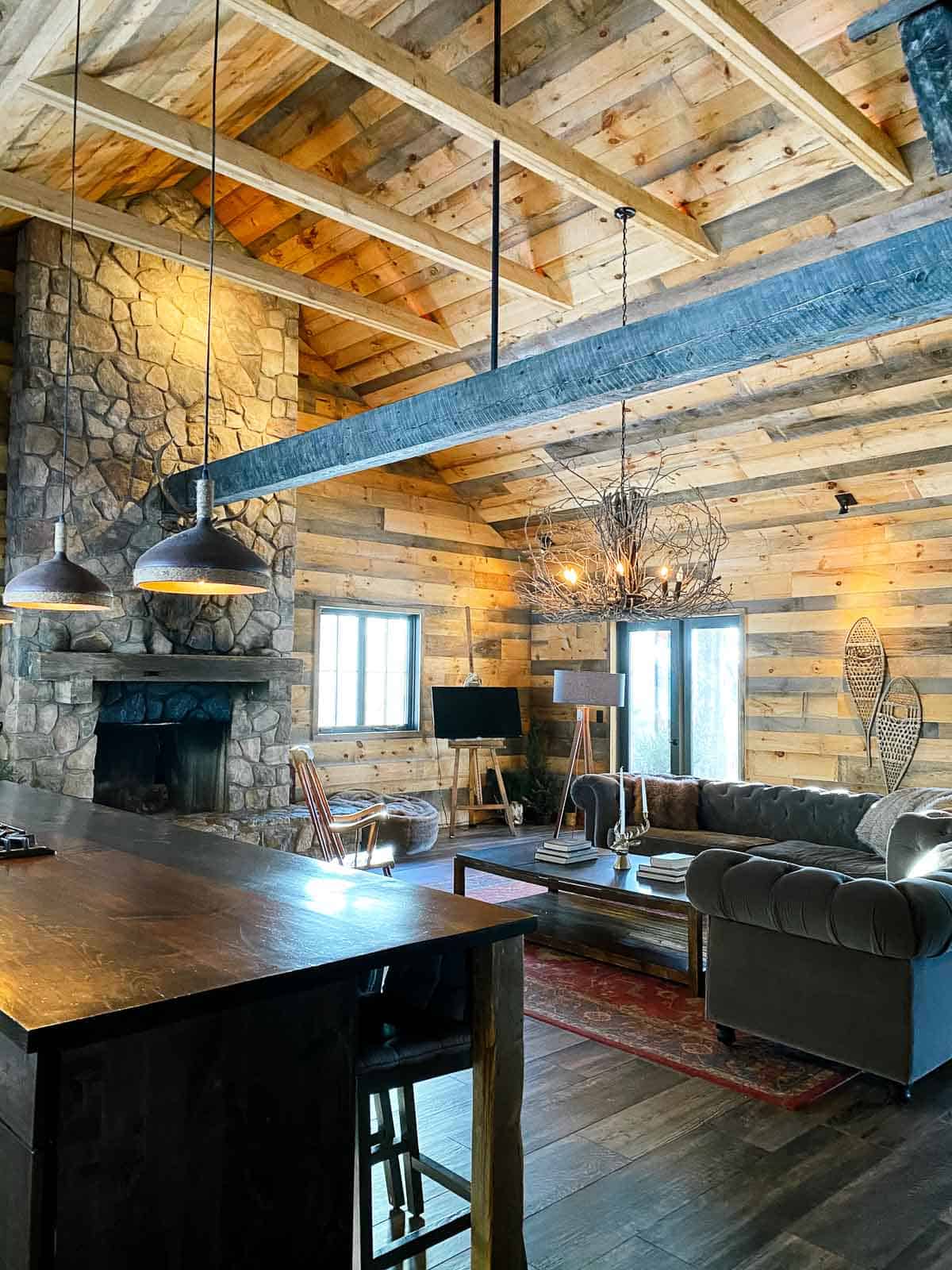 the lodge at june farms with wood beams and two grey couches and stone fireplace