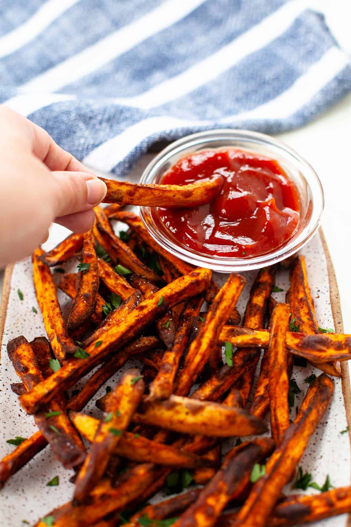 air fryer sweet potato fries dipping fry into side of ketchup blue napkin background