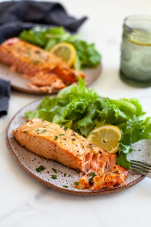 air fryer salmon fresh and frozen salmon fillet flakes two plates with lemon slice and lettuce