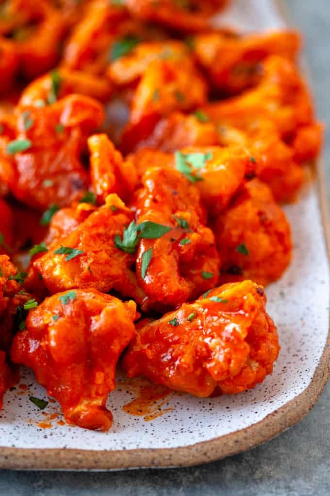 Bright red buffalo cauliflower wings close up with cilantro