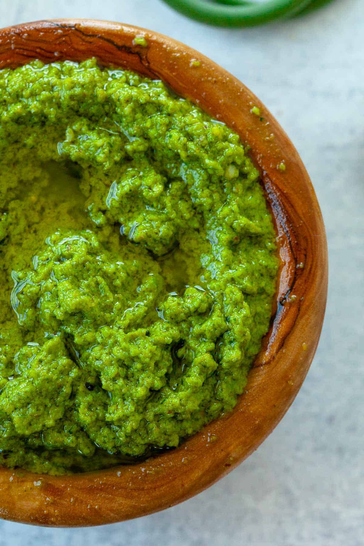 garlic scape pesto with olive oil in small brown wood bowl TeamJiX
