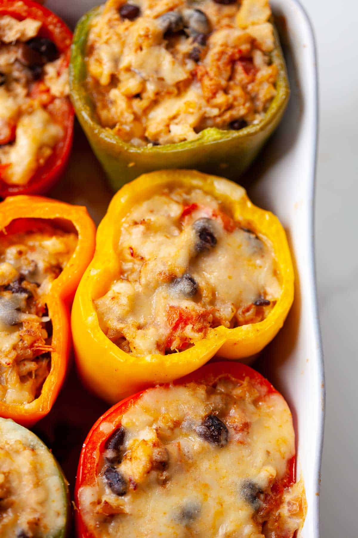 green yellow and red bell peppers stuffed with cheese and seafood in baking dish