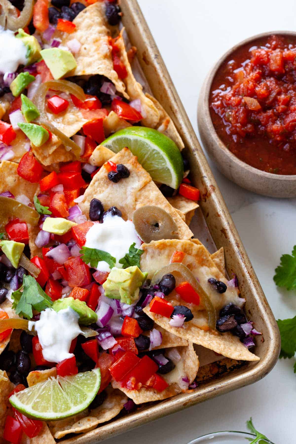 cerrar nachos vegetarianos con coberturas como aguacate, limas, cilantro y tazón de salsa al lado