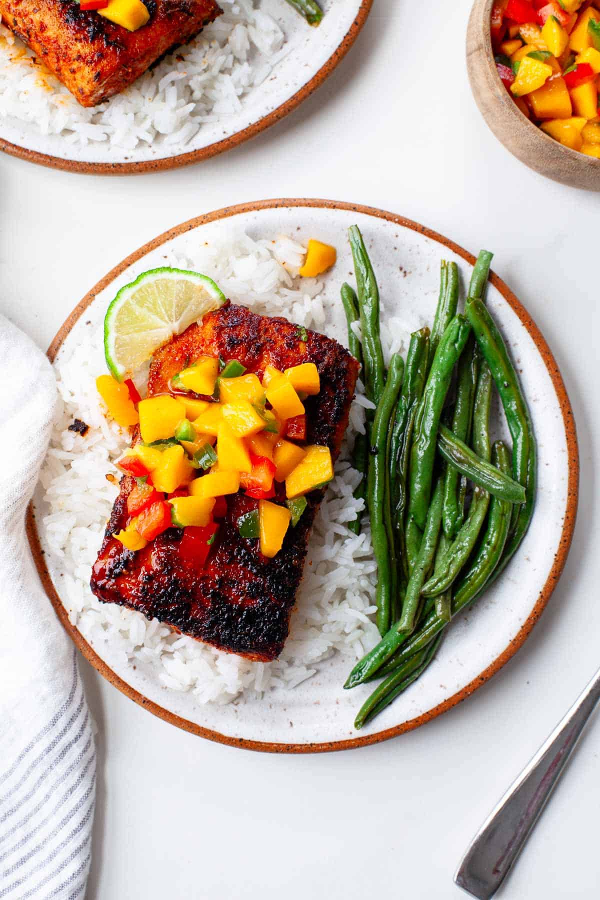 blackened mahi mahi on a bed of white rice, garnished with fresh mango salsa and served with a side of green beans