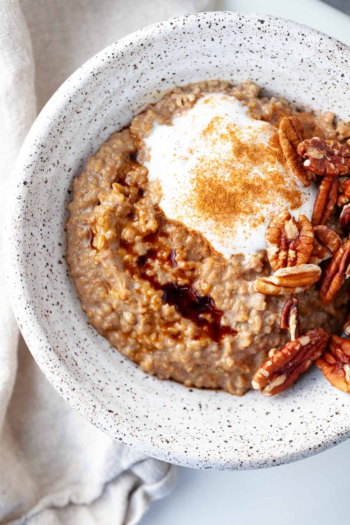 Gingerbread Oatmeal in a bowl speckled with yogurt, pecans, molasses and cinnamon.