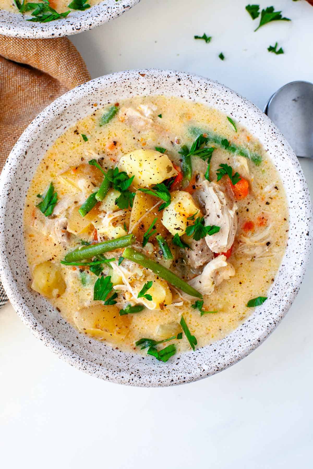 Instant Pot Chicken Stew served in a white speckled bowl garnished with freshly chopped parsley