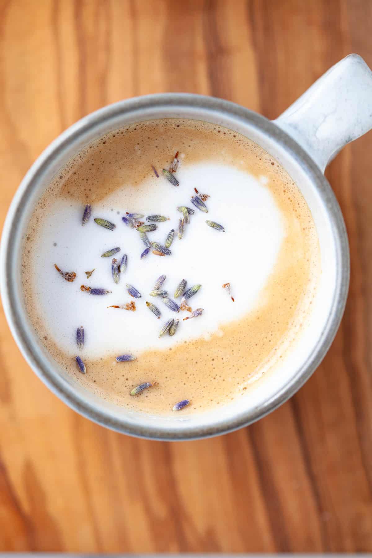 lavender latte in white mug with fresh foam and lavender buds on top