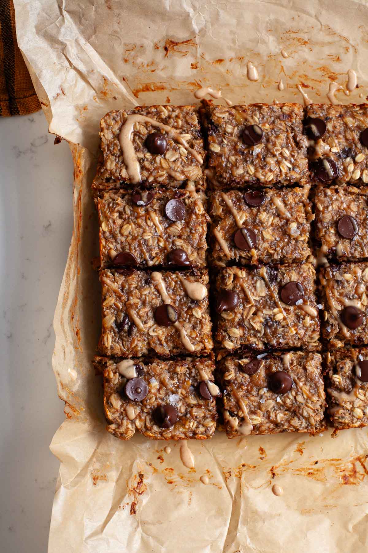 peanut butter banana oat bars with chocolate chips cut into squares on parchment paper