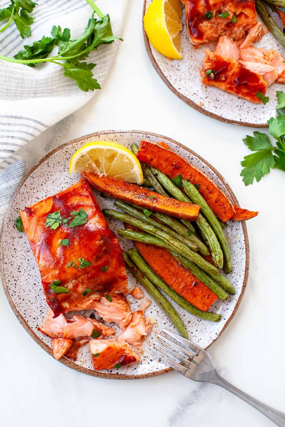 flaky BBQ salmon with roasted green beans and carrots on speckled plate